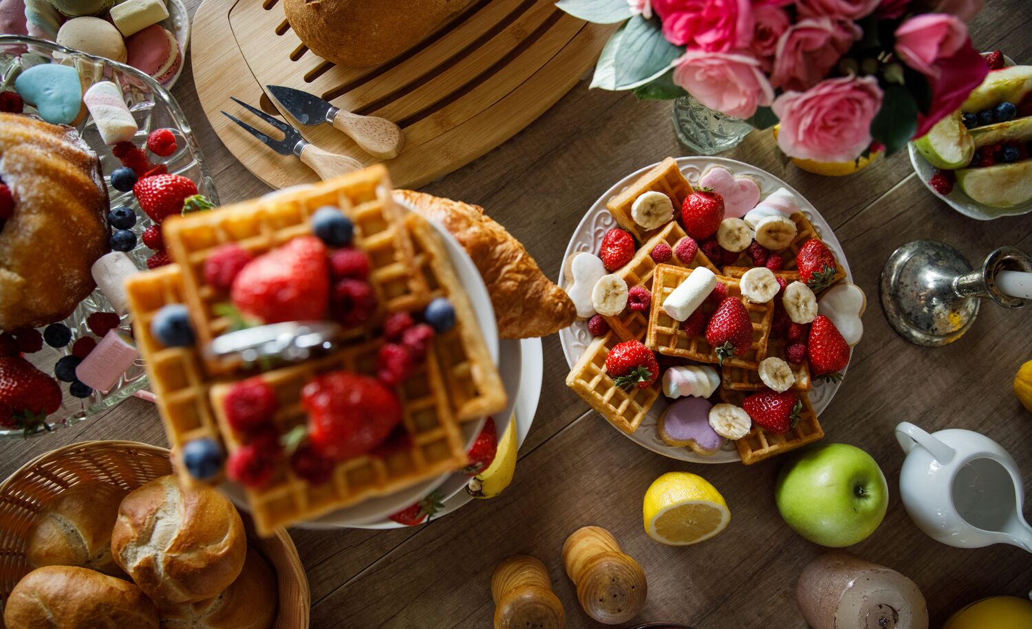 Brunch foods sit on a table including waffles, strawberries, apples, buns, and maple syrup at the Rimrock Resort in Banff National Park.